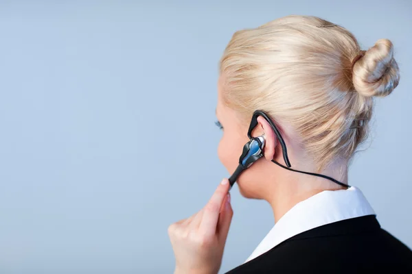 Kobieta rozmawia z naciskiem na zestaw słuchawkowy słuchawki — Zdjęcie stockowe