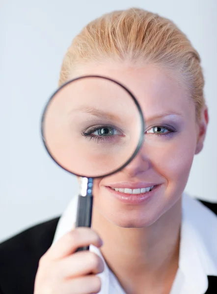 Smiling woman looking into a magniying glass — Stock Photo, Image