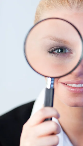 Smiling woman looking into a magniying glass — Stock Photo, Image