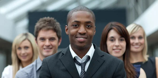 Empresario afroamericano sonriendo a la cámara con su equipo — Foto de Stock