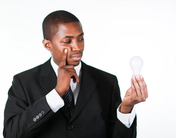 Pensativo empresario africano sosteniendo una bombilla — Foto de Stock
