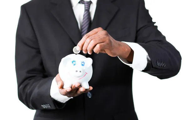 Close-up van een zakenman die geld steken in zijn piggy bank — Stockfoto