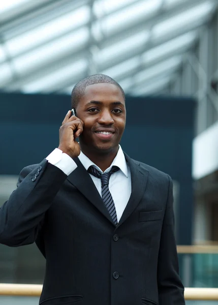 Etnische zakenman op telefoon en glimlachen naar de camera — Stockfoto