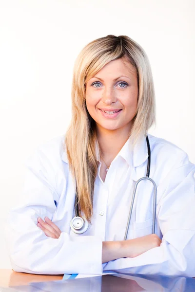 Blonde Ärztin sitzt in einem Büro und lächelt in die Kamera — Stockfoto