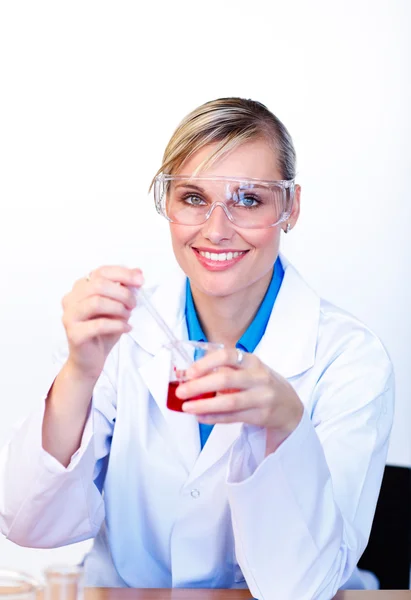 Cientista feminina examinando um tubo de ensaio e sorrindo para a câmera — Fotografia de Stock