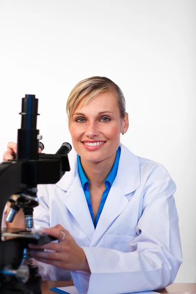 Cientista loira com um microscópio sorrindo para a câmera — Fotografia de Stock