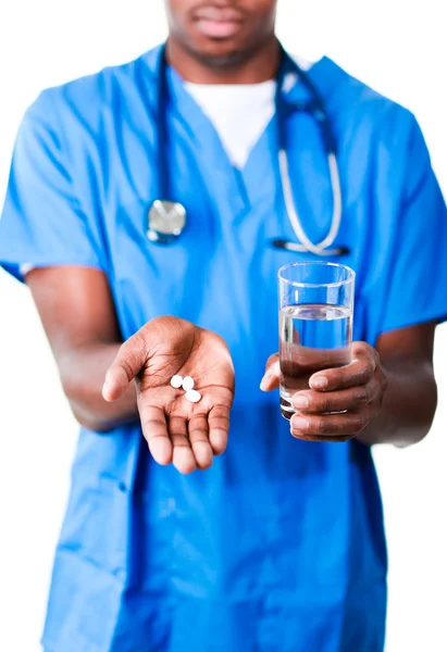 Young doctor holding pills and glass of water — Stock Photo, Image