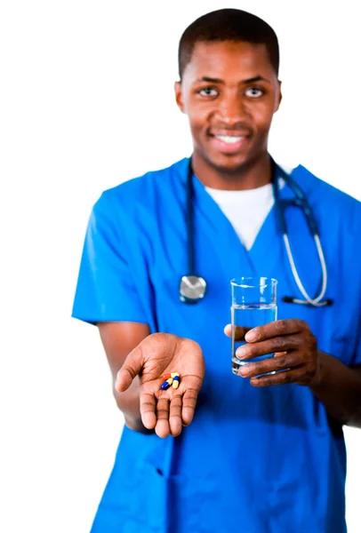 Портрет улыбающегося врача в униформе с таблетками и стаканом воды — стоковое фото