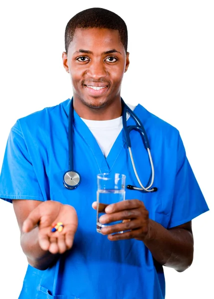 Médico sonriente en matorrales con pastillas y vaso de agua —  Fotos de Stock
