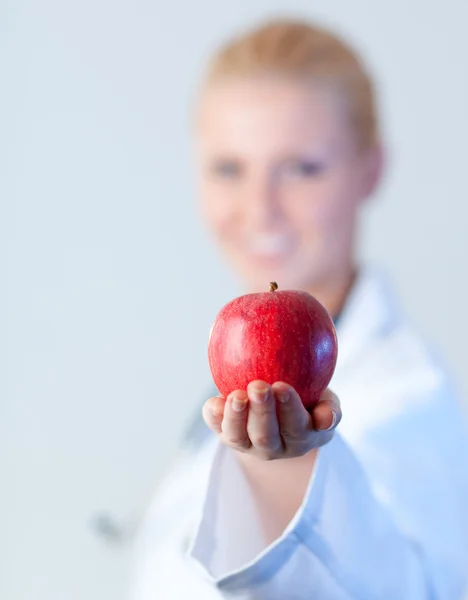 Doctor holding an apple with focus on the apple — Stock Photo, Image