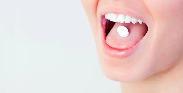 Kvinna med ett piller i hennes mun — Stockfoto
