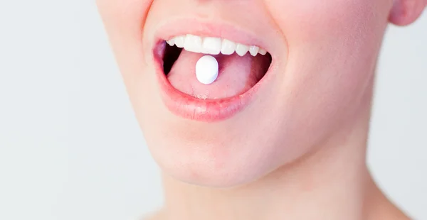 Frau mit Tablette im Mund — Stockfoto
