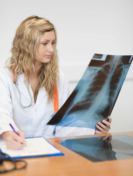Beautiful female surgeon holding a X-ray report — Stock Photo, Image