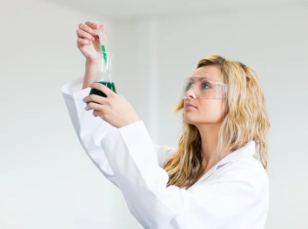 Mulher em lapcoat olhando para produtos químicos — Fotografia de Stock
