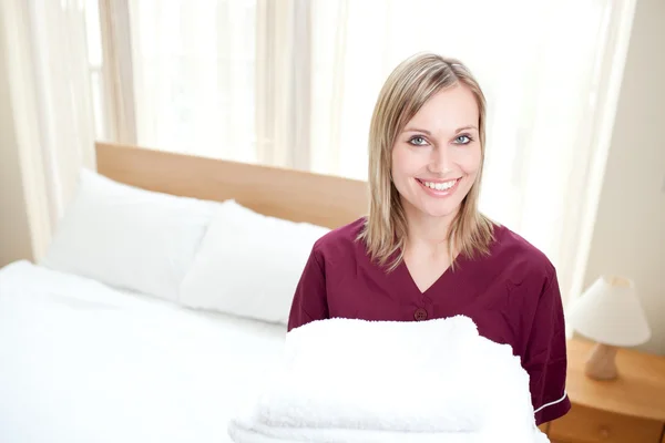 Señora de la limpieza radiante sosteniendo toallas en una habitación de hotel —  Fotos de Stock
