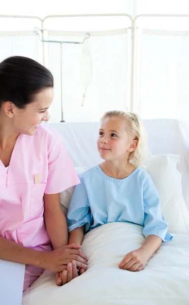 Enfermera sonriente llevando a una pequeña paciente femenina — Foto de Stock