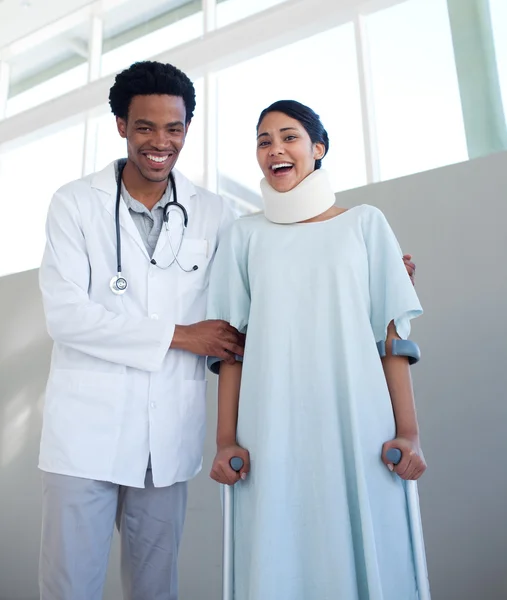 Usmívající se doktor pomáhá pacientka o berlích — Stock fotografie