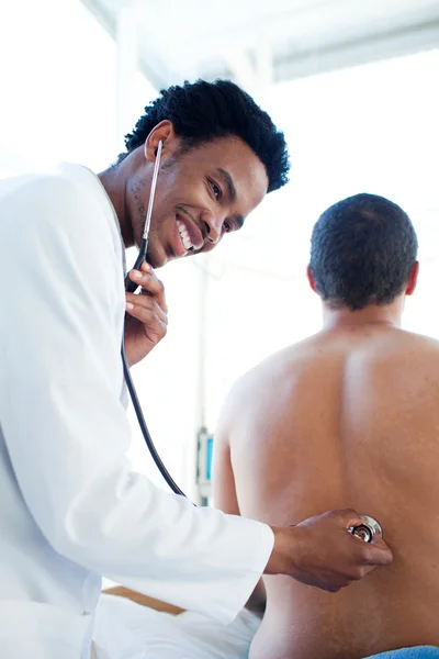 Médico afro-americano que atende um paciente do sexo masculino — Fotografia de Stock