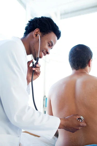 Jovem médico examinando um paciente — Fotografia de Stock