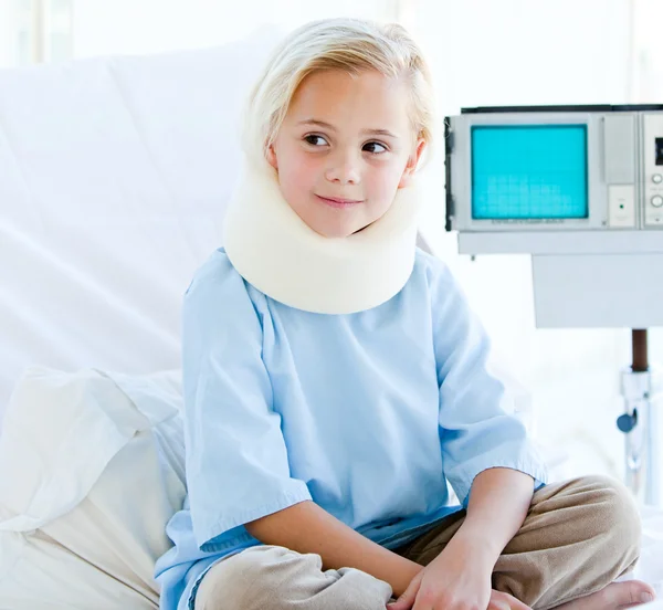 Маленька дівчинка з брекетом для шиї сидить на лікарняному ліжку — стокове фото