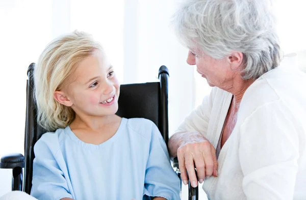 Nettes kleines Mädchen, das im Rollstuhl sitzt und mit ihrer Oma spricht — Stockfoto