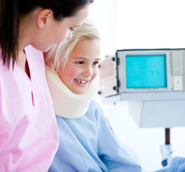 Menina sorridente com uma cinta no pescoço sentado em uma cama de hospital — Fotografia de Stock