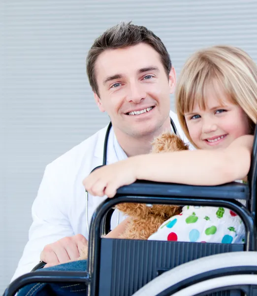 Cute little girl sitting on a wheelchair with her doctor — Stock Photo, Image