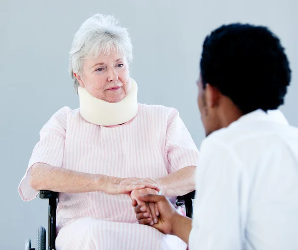 Senior woman sitting on a wheelchair with a neck brace talking w — Stock Photo, Image