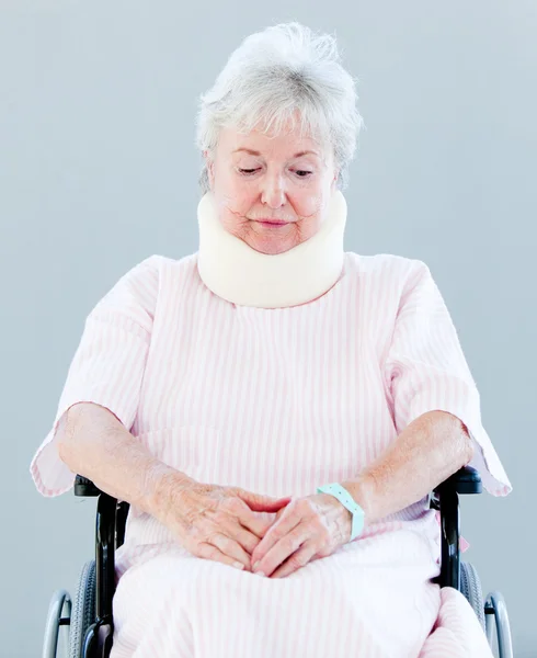 Femme âgée bouleversée avec une attelle de cou assise sur un fauteuil roulant — Photo