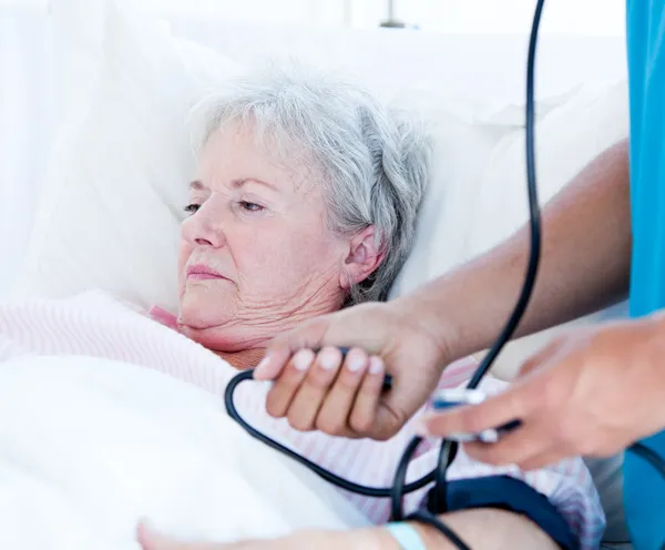 Άρρωστος ανώτερος γυναίκα ξαπλωμένο σε ένα κρεβάτι νοσοκομείου — Φωτογραφία Αρχείου