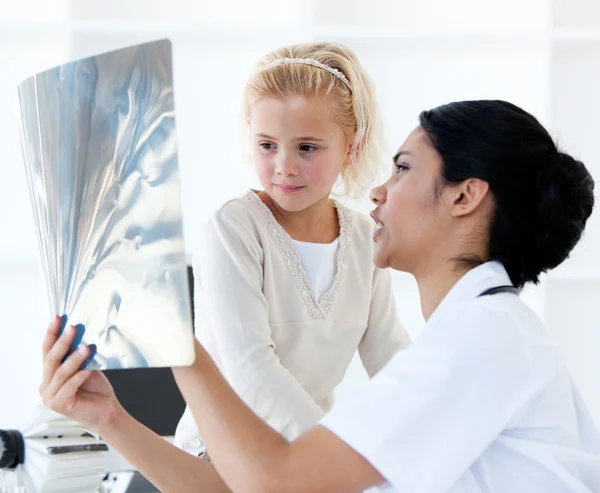 Selbstbewusste Ärztin zeigt einem kleinen Mädchen ein Röntgenbild — Stockfoto