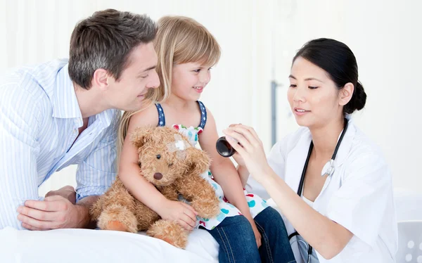 Concentrated asian female doctor giving syrup to a little girl — Stock Photo, Image