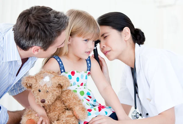 Сияющая женщина-врач осматривает маленькую девочку с медицинским оборудованием — стоковое фото
