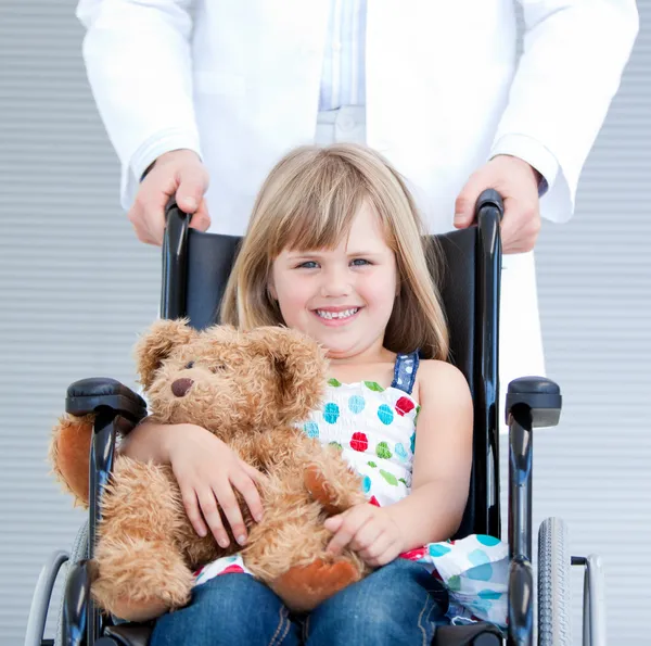 Porträtt av en liten flicka sitter på rullstolen stöds av — Stockfoto