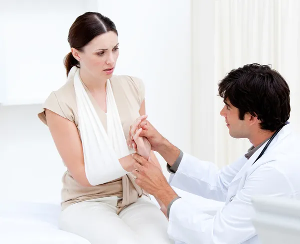 Joven médico masculino examinando a la paciente femenina tomando su brazo — Foto de Stock