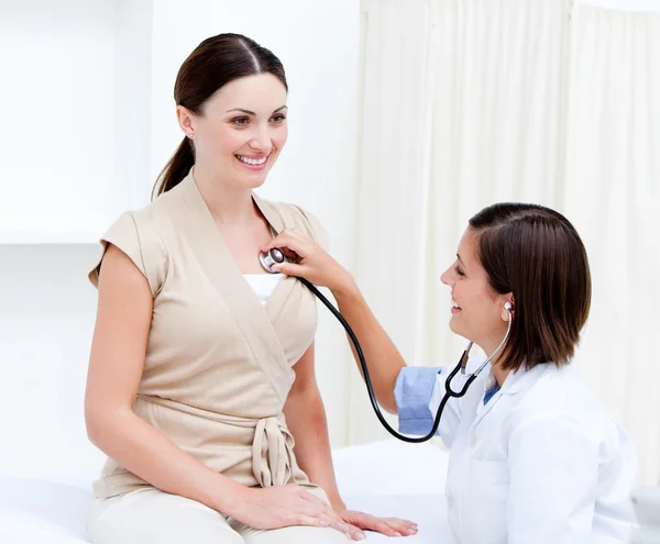 Pěkný ženský lékař zkoumá pacienta s její stetoskop — Stock fotografie