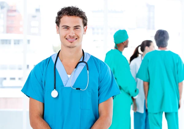 Handsome male doctor looking at the camera while his medical par — Stock Photo, Image