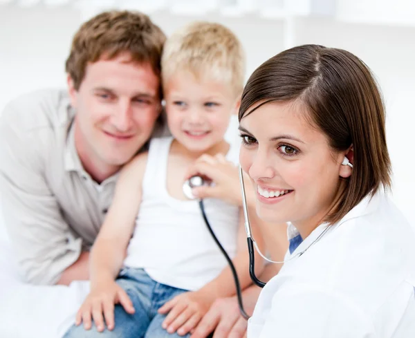 그의 아버지와 함께 어린 아이 검사 하는 아름 다운 여성 의사 — 스톡 사진