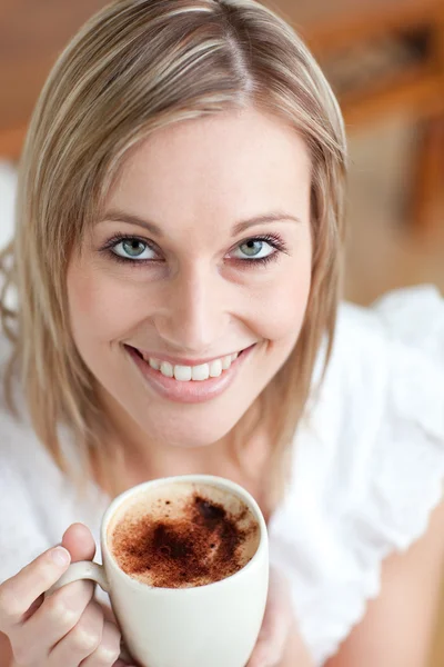 Bright woman drinking a coffee sitting on a sofa — Stock Photo, Image