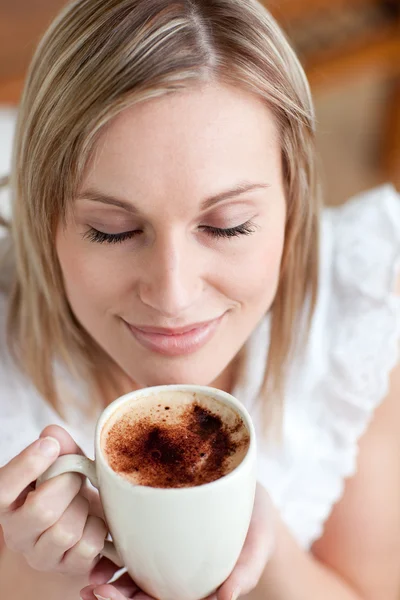 Attraktiv kvinna dricker en kaffe som sitter på en soffa — Stockfoto