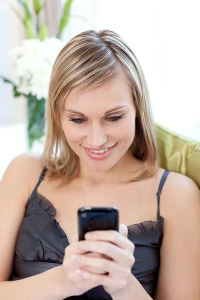Vacker kvinna skicka en text som sitter på en soffa — Stockfoto