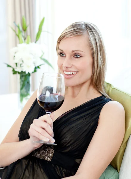 Счастливая женщина пьет красное вино сидя на диване — стоковое фото