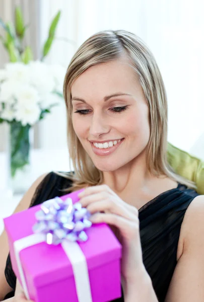 Mutlu bir kadın kanepede oturan bir hediye açılış — Stok fotoğraf