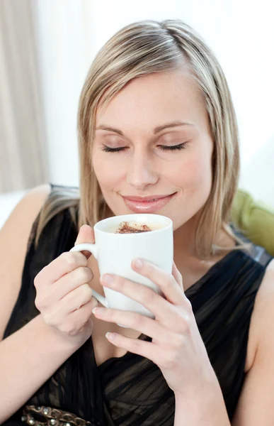 Ontspannen vrouw drinken een kopje koffie zittend op een bank — Stockfoto