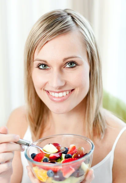 Mulher alegre comendo uma salada de frutas — Fotografia de Stock
