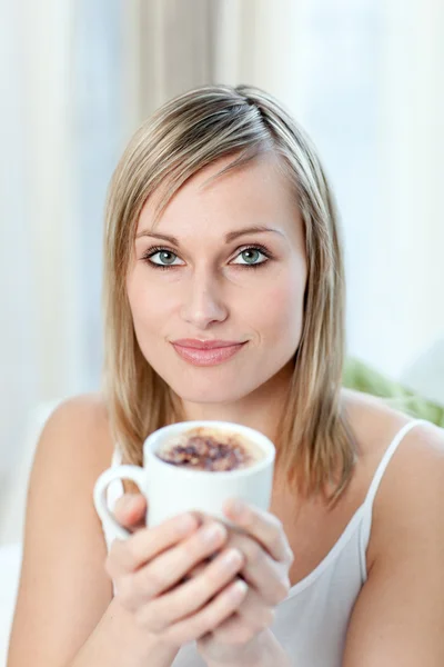 Portret młodej kobiety, picie kawy, siedząc na kanapie — Zdjęcie stockowe