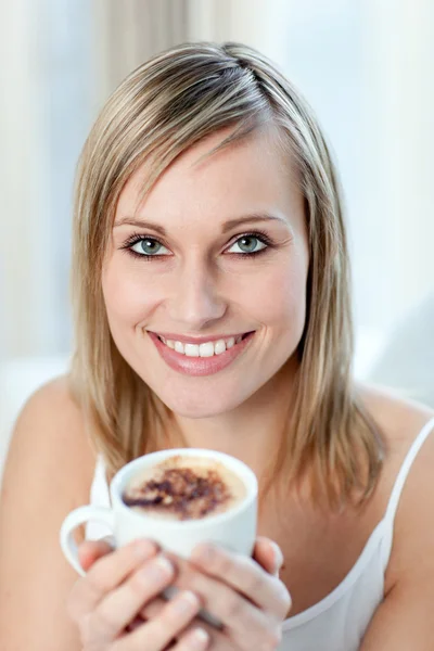 Retrato de uma mulher feliz bebendo um café sentado em um sofá — Fotografia de Stock
