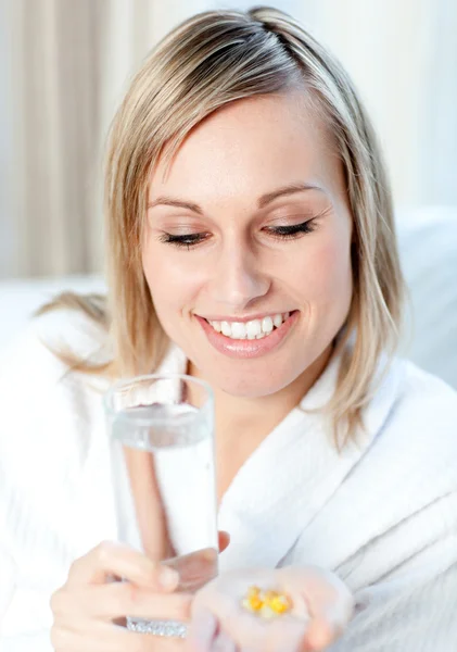 Donna bionda malata con in mano un bicchiere d'acqua e pillole — Foto Stock
