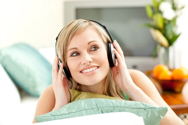 Czarujący blond kobieta słuchania muzyki leżąc na kanapie — Zdjęcie stockowe