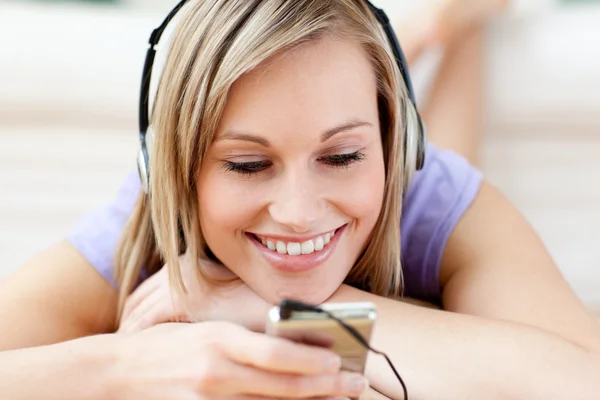 Cheerful woman listening music lying on the floor — Stock Photo, Image